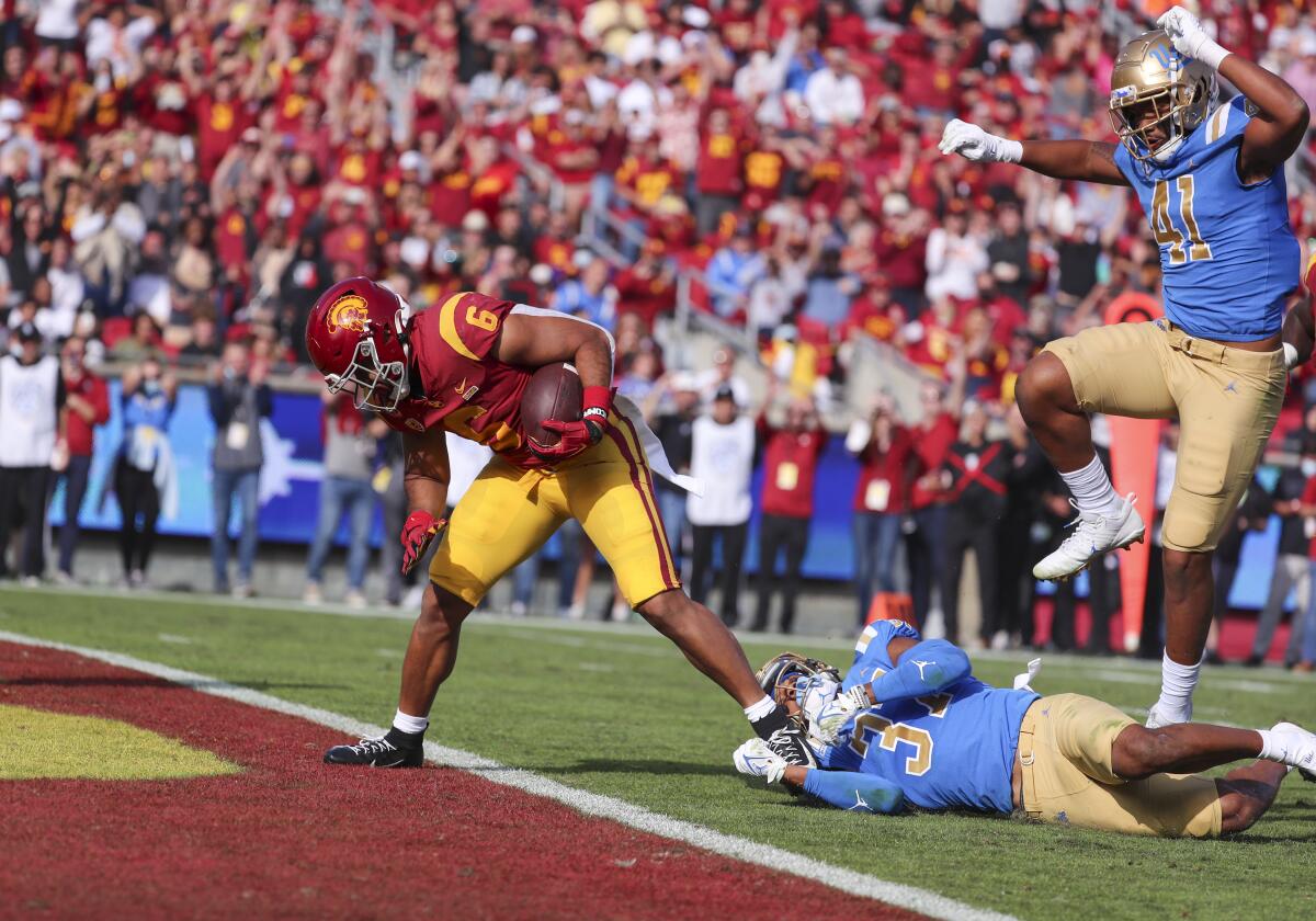 USC tailback Vavae Malepeai scores past UCLA defensive back Quentin Lake and defensive back Jelani Warren.