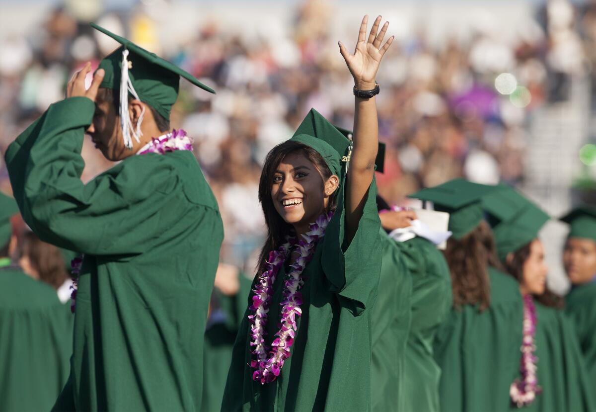 Arlene Santiago waves to family and friends in the stands during Costa Mesa High School's Class of 2015 graduation ceremony at Jim Scott Stadium on Thursday.