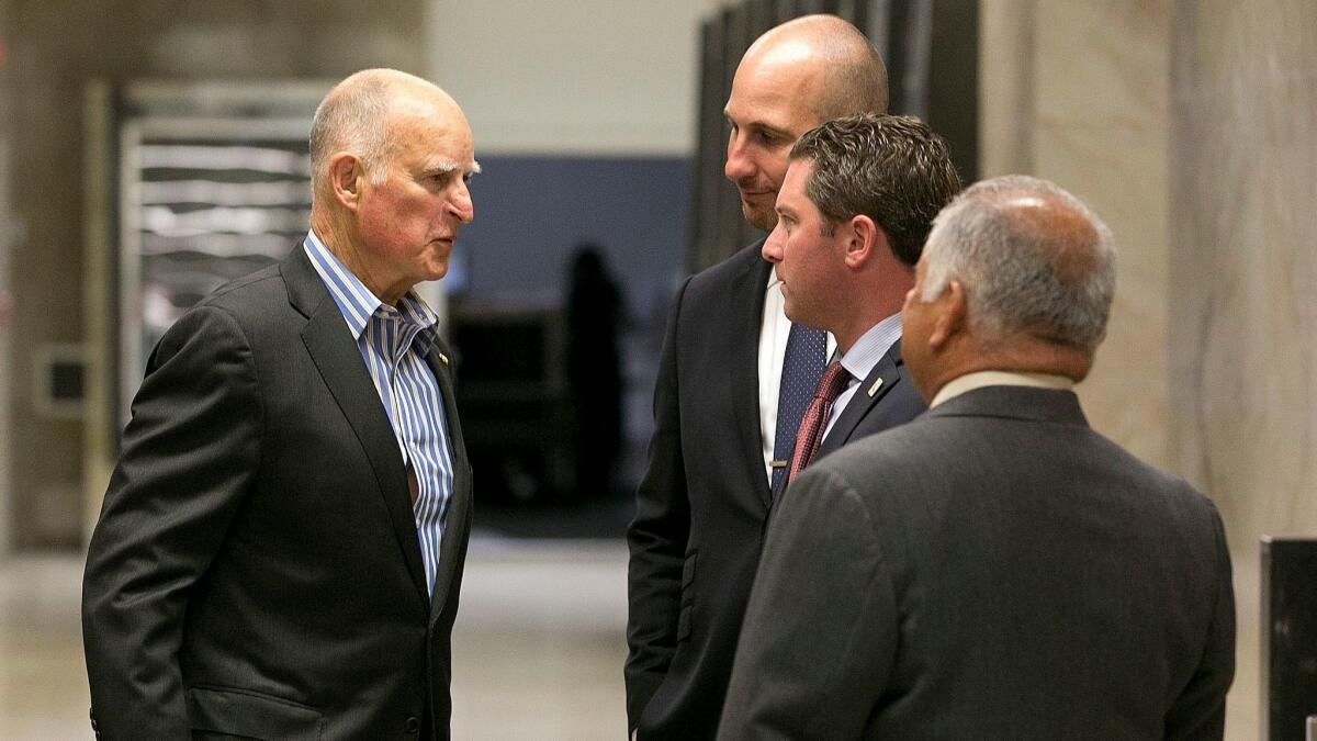 Gov. Jerry Brown, left, chats with Republican Assemblymen Heath Flora of Ripon, Jordan Cunningham of Templeton and Rocky Chavez of Oceanside on July 17. They were among eight Republicans who voted with Democrats to extend the cap-and-trade program.