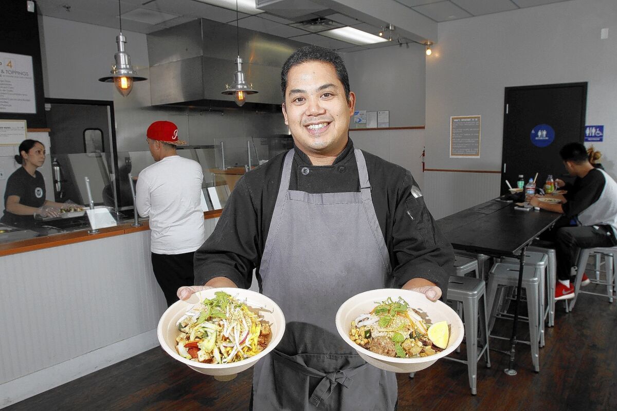 Lawrence Sevilla holds a chicken and rice bowl, left, along with a meatball and noodles bowl, right, at The Asian Project in Burbank, photographed on Thursday, May 22, 2014.