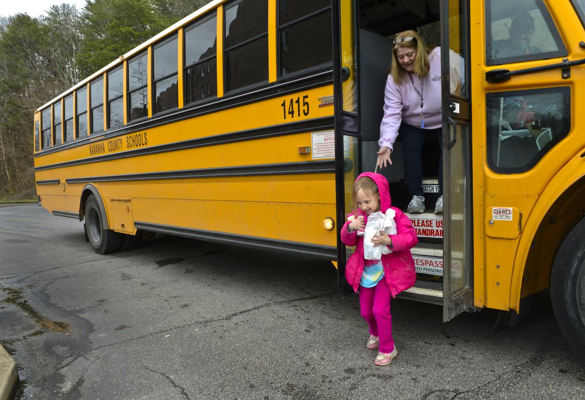 Amira Sexton, 6, of Charleston, W.Va., picks up a breakfast and a lunch that were delivered March 16 by her school bus driver Rob Rider and bus aide Rosemary Light.