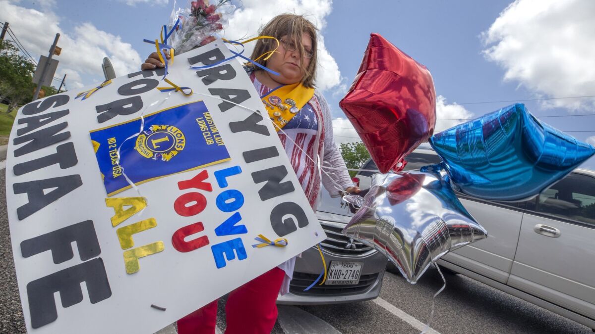 Lucy Gonzales of League City, Texas, carries flowers, a sign and balloons outside Santa Fe High School on Saturday. Students and teachers were allowed back to parts of the school to retrieve their belongings.