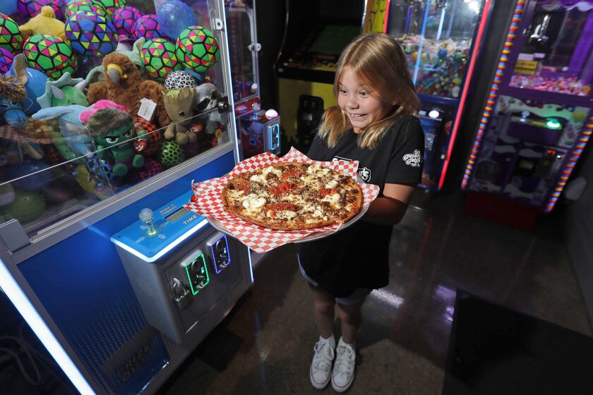 Paige Roberts, 9, holds the special Da Rulk Pie, a pizza in honor of Julian Dunn at Sgt. PepperoniOs Pizza game room in Newport Beach. The restaurant is raising funds and collecting LEGO¨ sets in partnership with JulianOs LEGO¨ Corner at CHOC hospital. Julian Dunn was a neighbor of the girls' who was also a cancer patient at CHOC hospital.