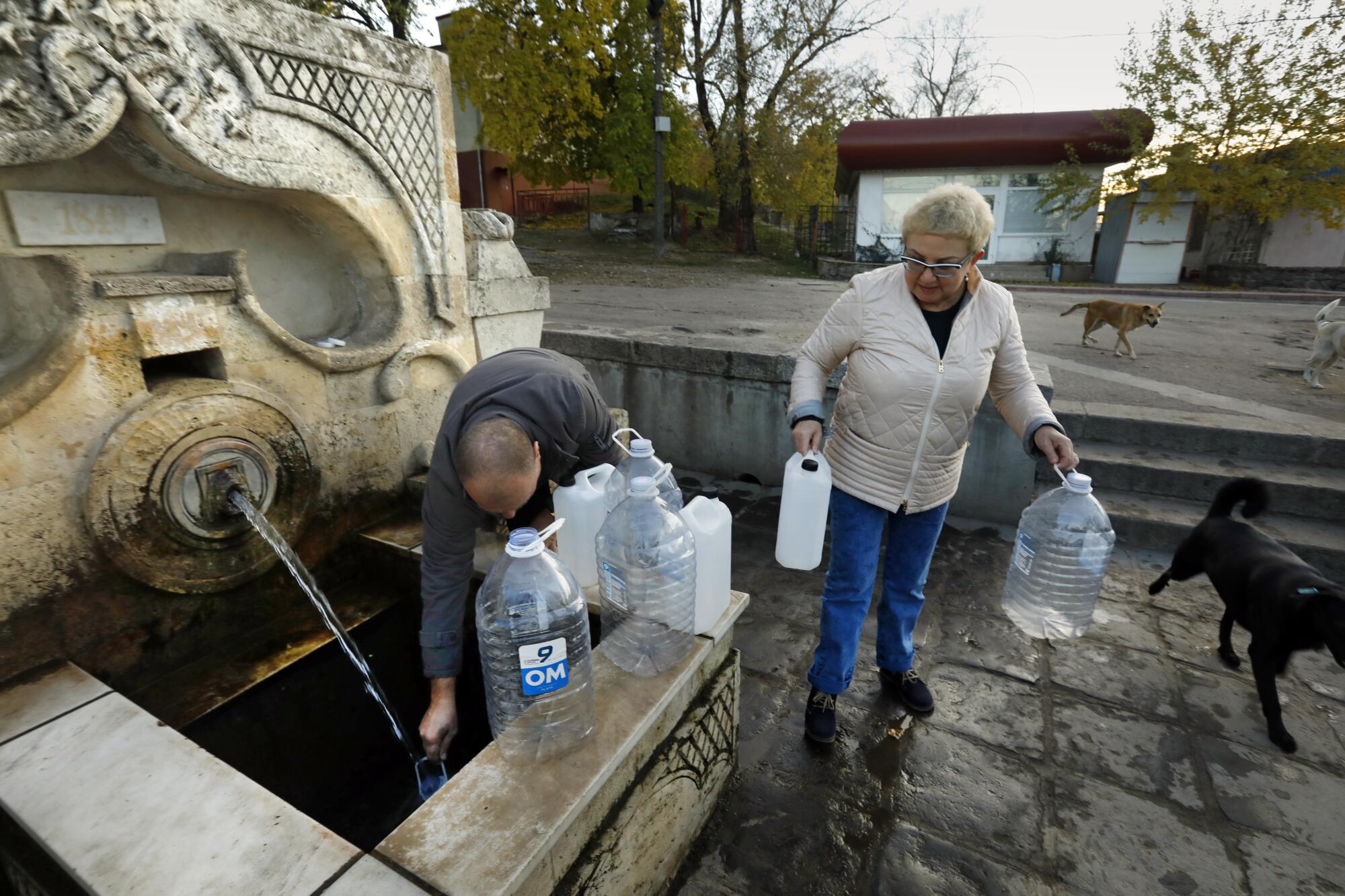 Families brings bottles to fill with clean water at a park in Mykolaiv.