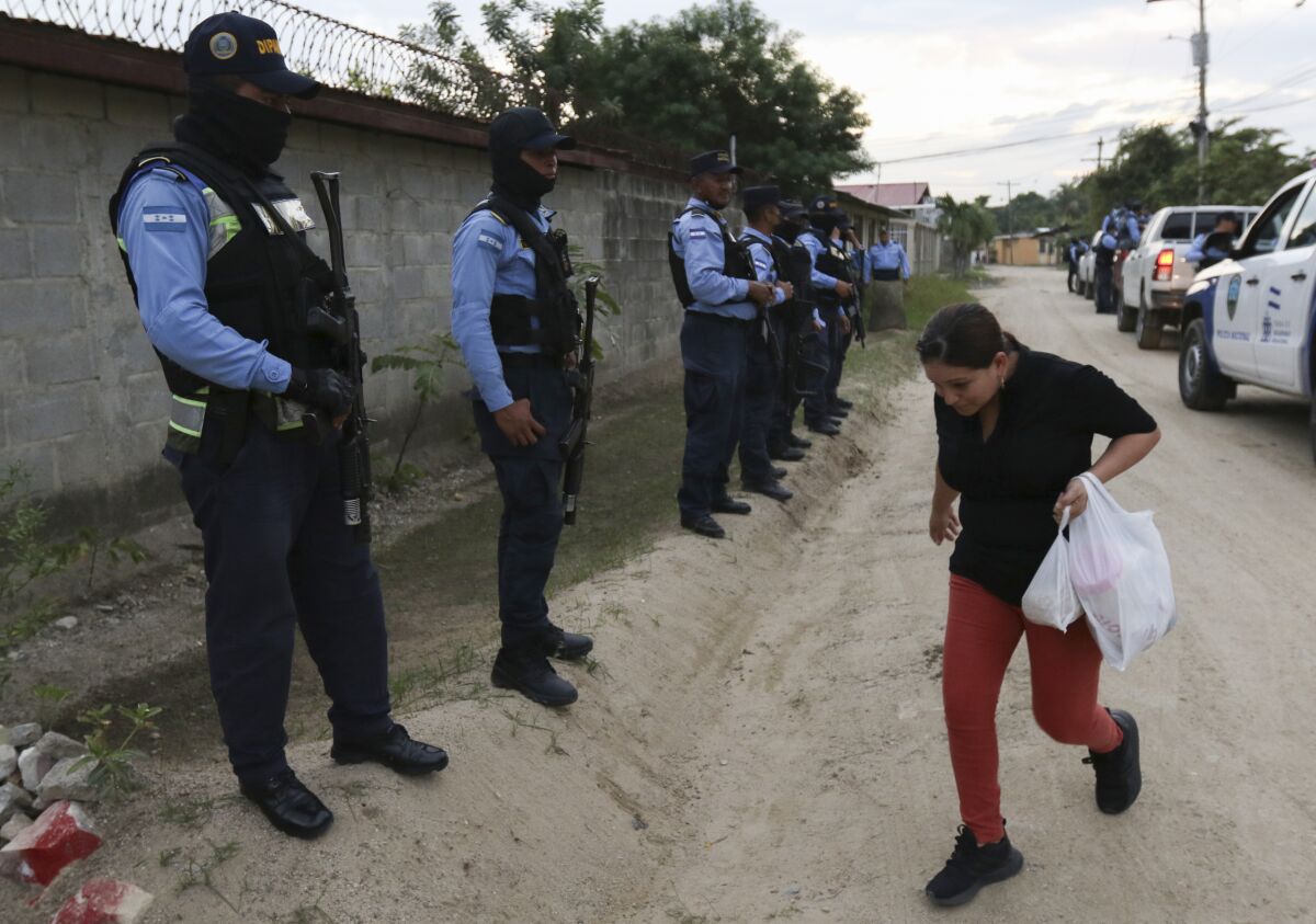 A woman looks at the ground as she walks past a line of police officers in San Pedro Sula, Honduras.