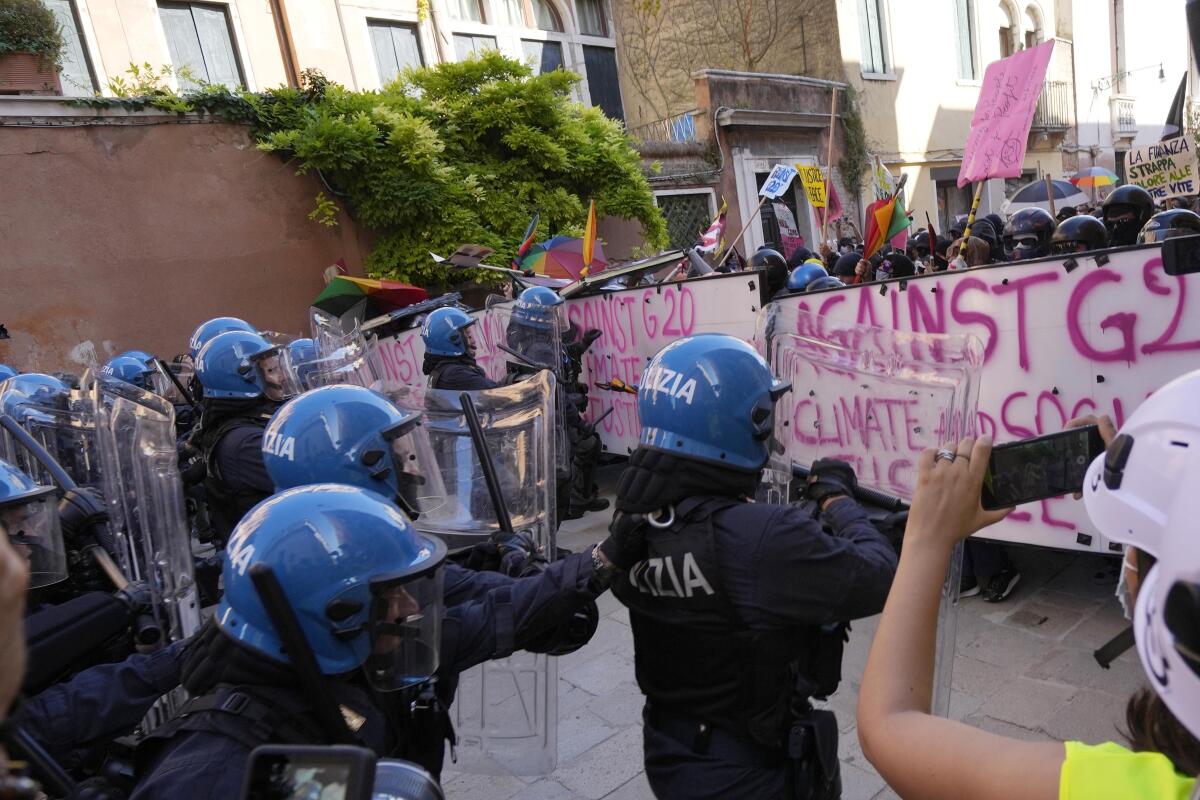 Police in riot gear face off against a line of protesters holding anti-G-20 banners.