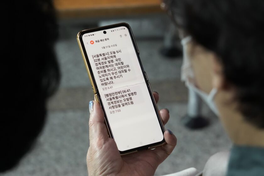 A woman looks at her mobile phone with an emergency evacuation warning text message sent to Seoul residents as she watches a news program at the Seoul Railway Station in Seoul, South Korea, Wednesday, May 31, 2023. North Korea's attempt to put the country's first spy satellite into space failed Wednesday in a setback to leader Kim Jong Un's push to boost his military capabilities as tensions with the United States and South Korea rise. (AP Photo/Ahn Young-joon)