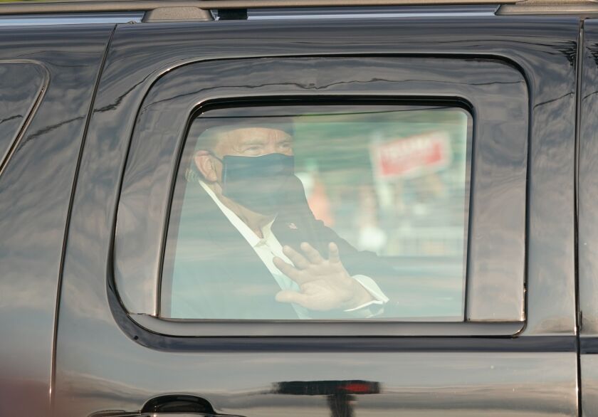 President Trump waves from the back of a car in a motorcade outside Walter Reed National Military Medical Center.
