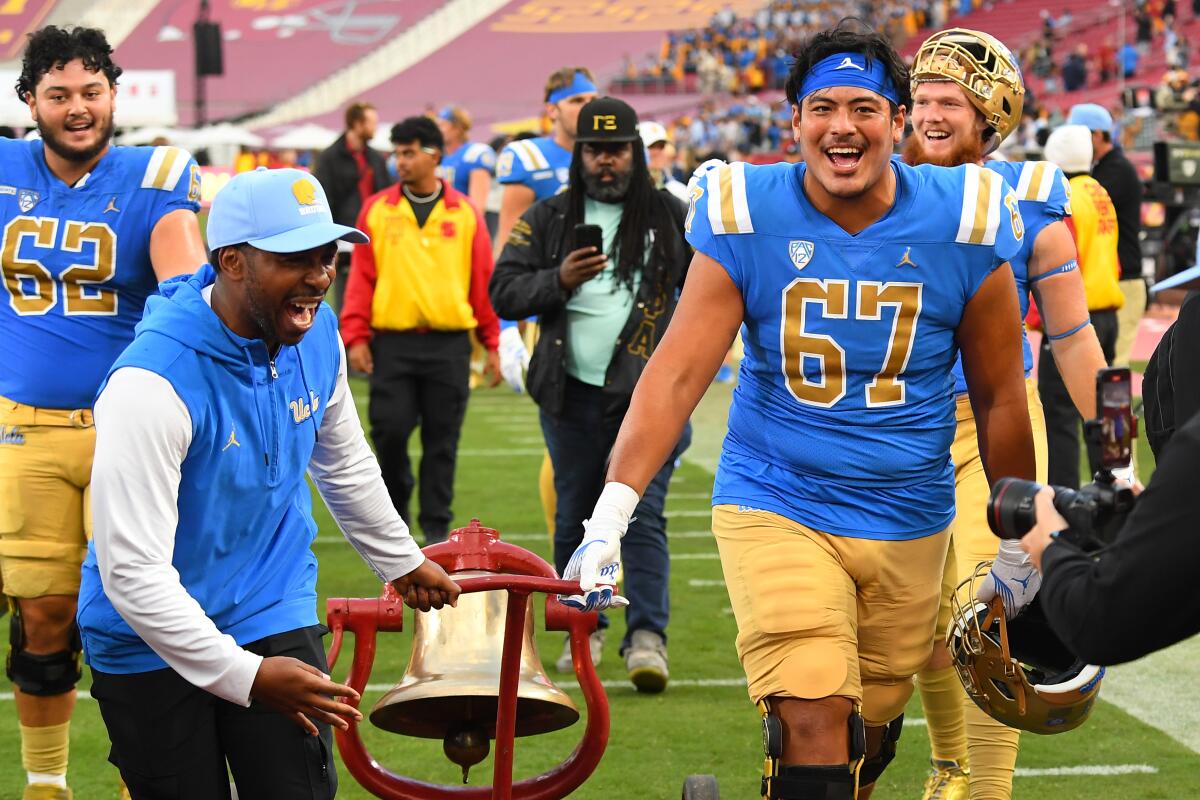 Le directeur sportif de l'UCLA, Martin Jarmond, et le joueur de ligne offensive Yutaka Mahe lancent la cloche de la victoire sur le terrain du Coliseum. 