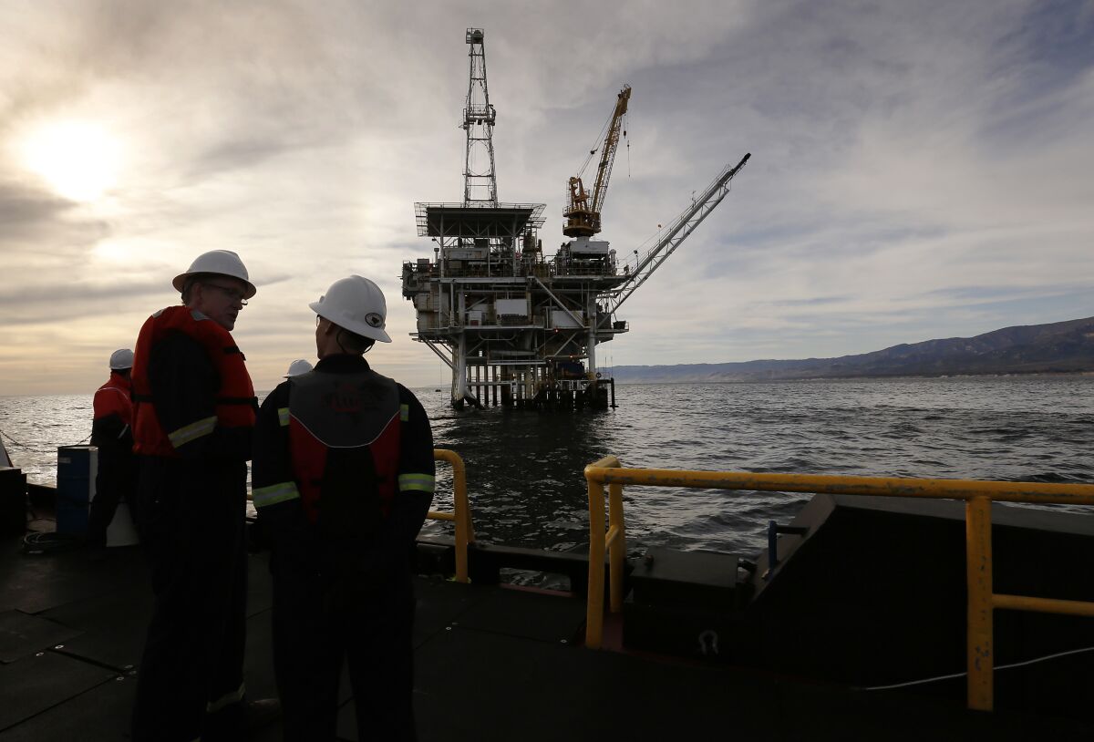 Chris Peltonen, left, watches as the boat pulls away from the oil platform Holly in 2018.