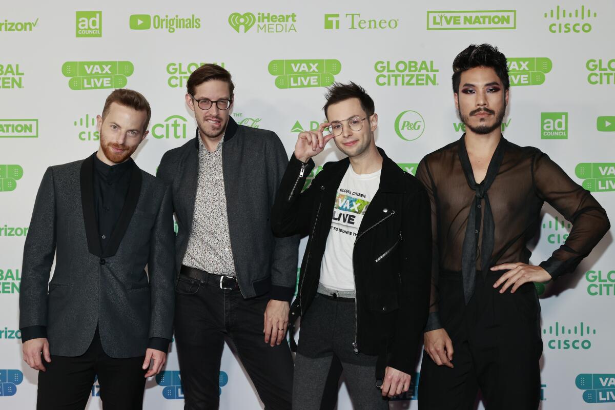Four men pose on the red carpet at an event