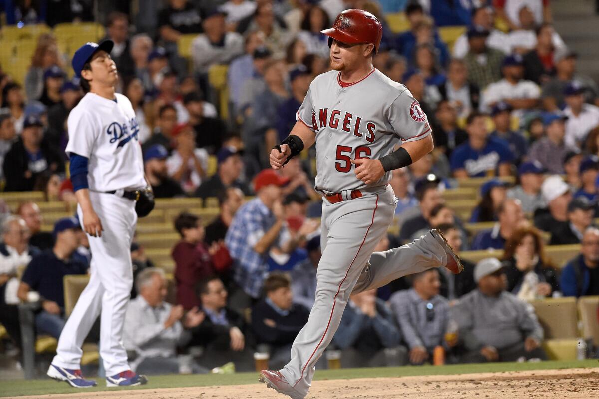 Angels outfielder Kole Calhoun (56) scores in the third inning against as Dodgers starting pitcher Kenta Maeda looks on.