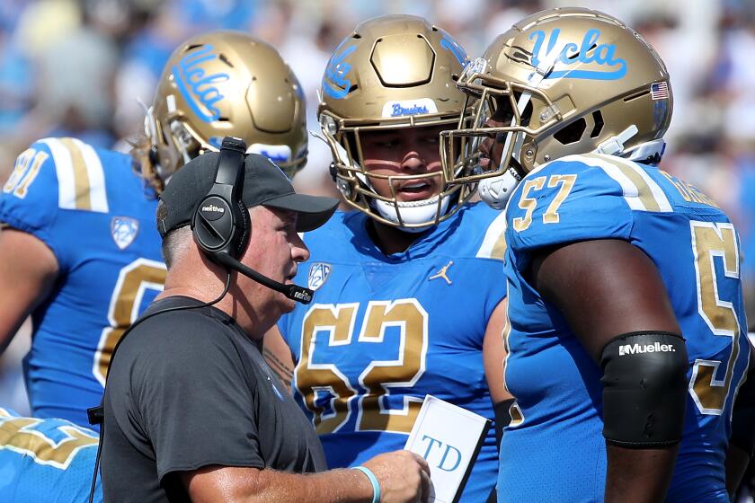 UCLA coach Chip Kelly talks with his players on the sideline during a 2022 game 