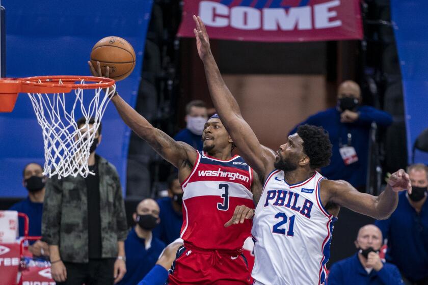 Washington Wizards guard Bradley Beal, left, goes up for the shot against Philadelphia 76ers center Joel Embiid, right, during the second half of an NBA basketball game, Wednesday, Jan. 6, 2021, in Philadelphia. The 76ers won 141-136. (AP Photo/Chris Szagola)