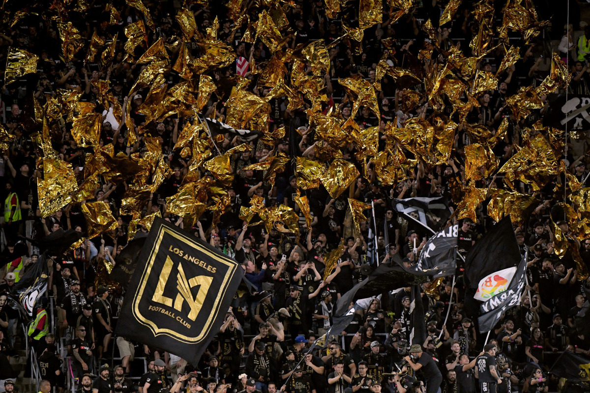 An aerial view of a dense crowd; some hold up a flag that says "Los Angeles Football Club."