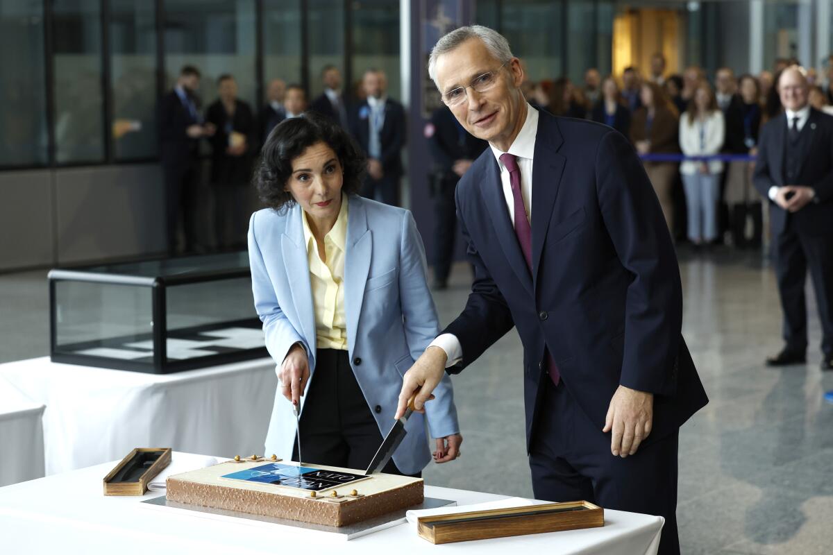 NATO Secretary General Jens Stoltenberg, right, and Belgium's Foreign Minister Hadja Lahbib cut a cake.