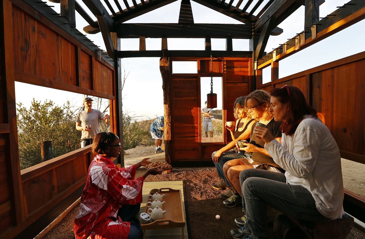 Tiffany Williams pours tea for Stacey Abarbanel, Karin Huebner and Michele Raitano at an artist-built teahouse that was built overnight in Griffith Park. Constructed surreptitiously by an anonymous collective of artists, it was inaugurated on Tuesday morning with tea, cookies and opera.