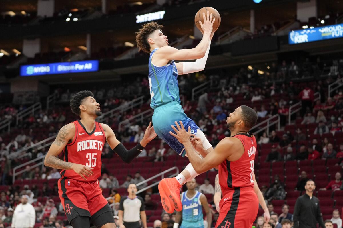 Charlotte Hornets guard LaMelo Ball puts up a shot between Houston's Christian Wood, left, and Eric Gordon.