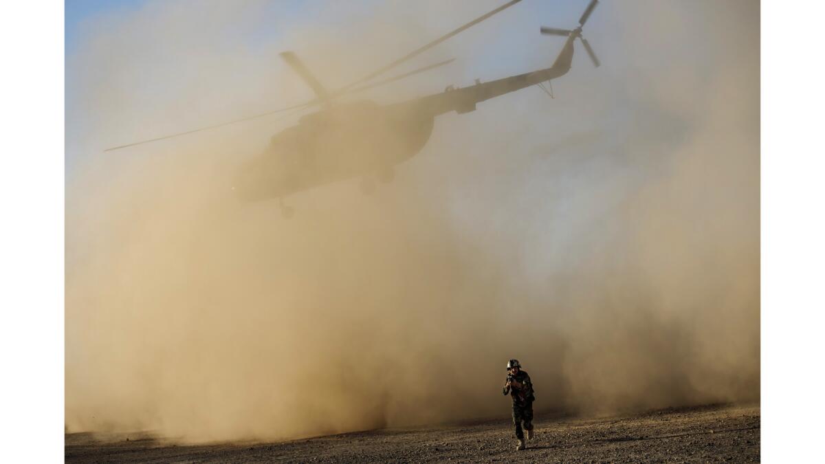 A soldier with the Afghan army leaves the landing site as an Afghan Mi-17 takes off during training near Camp Shorab, in Helmand Province.