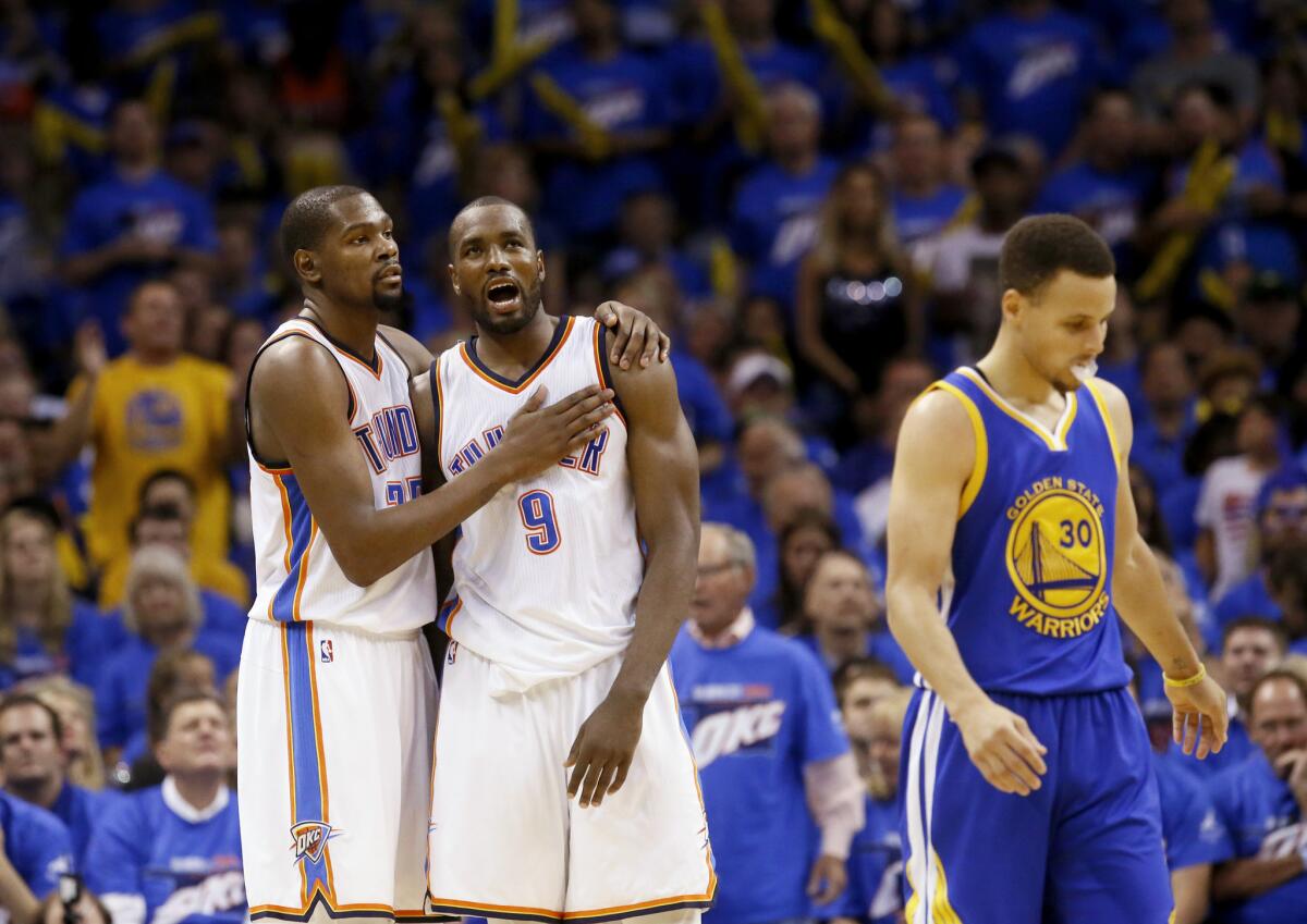 The Thunder's Kevin Durant embraces teammate Serge Ibaka as the Golden State Warriors' Stephen Curry walks away during a playoff game in Oklahoma City on May 22.