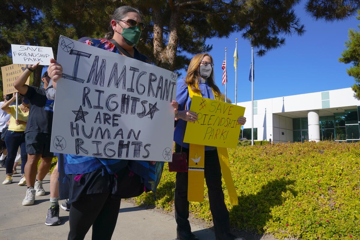 People hold signs reading "Immigrant Rights Are Human Rights" and "Save Friendship Park."
