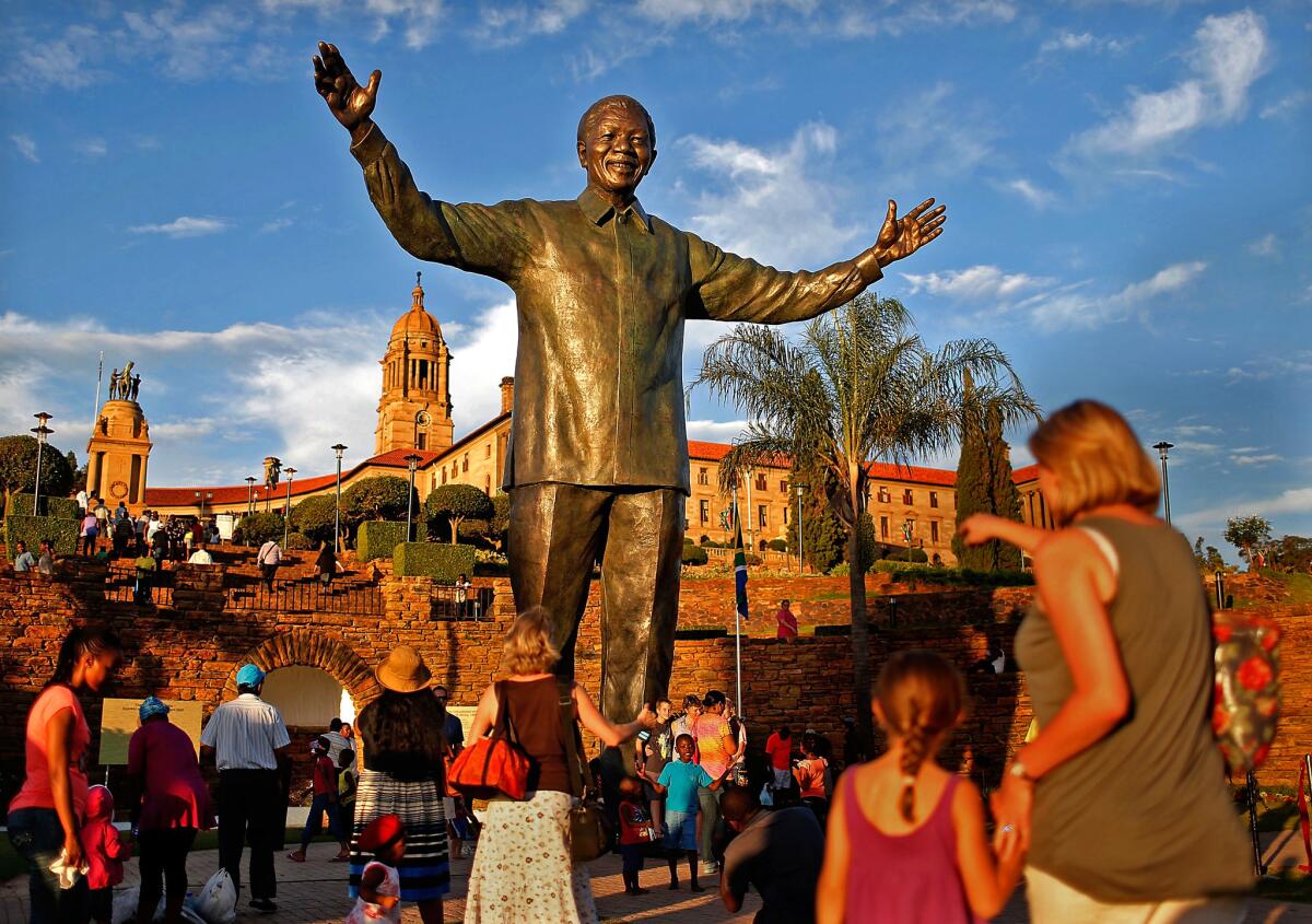 Visitors take photos of the statue of former South African President Nelson Mandela in Pretoria, South Africa.