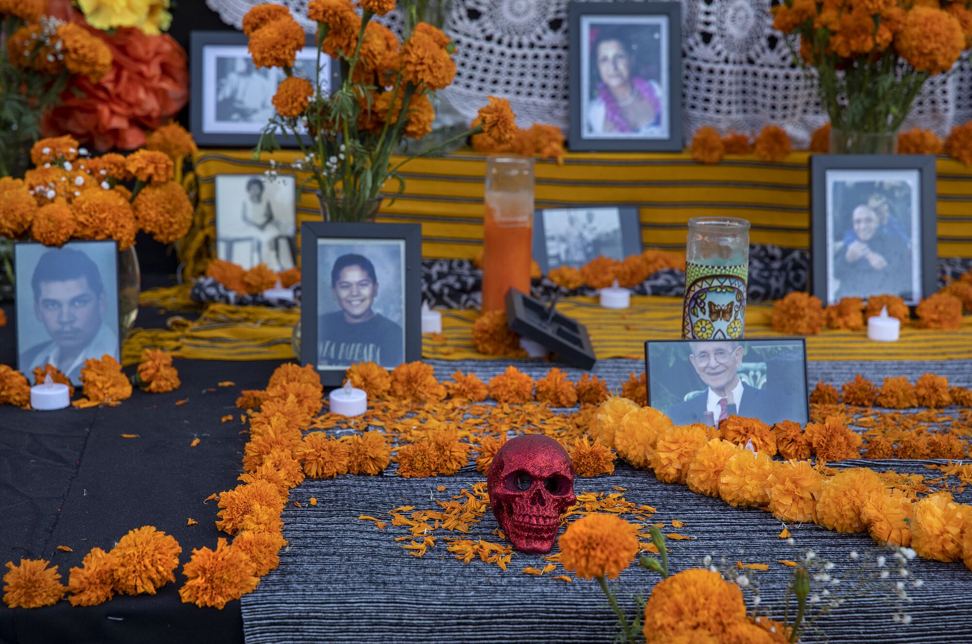 Photos of individuals are seen among orange carnations in the community altar.