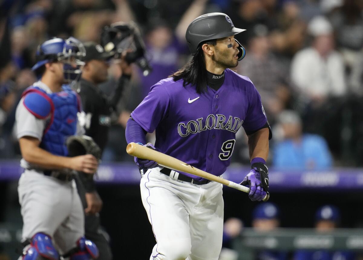 The Rockies' Connor Joe follows the flight of his home run in as Dodgers catcher Austin Barnes looks on April 9, 2022.