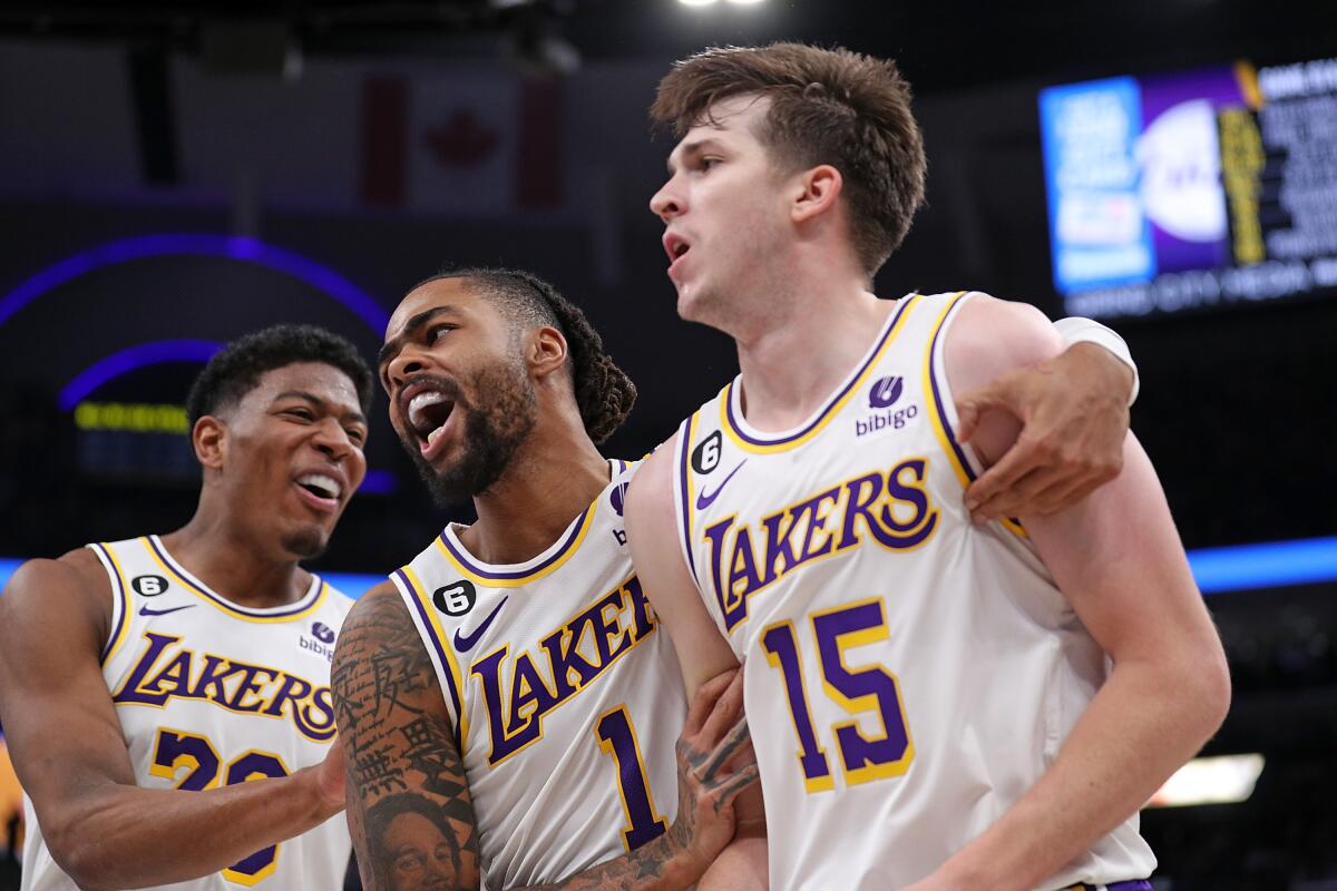Lakers teammates, from left, Rui Hachimura, D'Angelo Russell and Austin Reaves celebrate on the court.