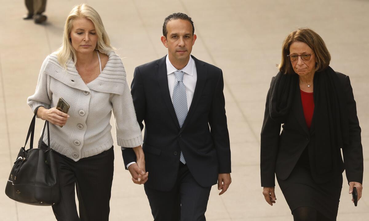 A couple hold hands as a woman walks alongside them