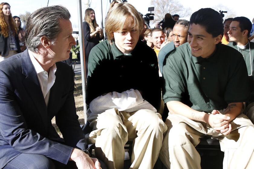Gov. Gavin Newsom talks with Juan Cruz Lopez Jr. right, a youthful offender at the O.H. Close Youth Correctional Facility, Tuesday, Jan. 22, 2019, in Stockton, Calif. Newsom is proposing to put California's juvenile prisons under the state's Health and Human Services Agency instead of the same agency that runs adult prisons. (AP Photo/Rich Pedroncelli)