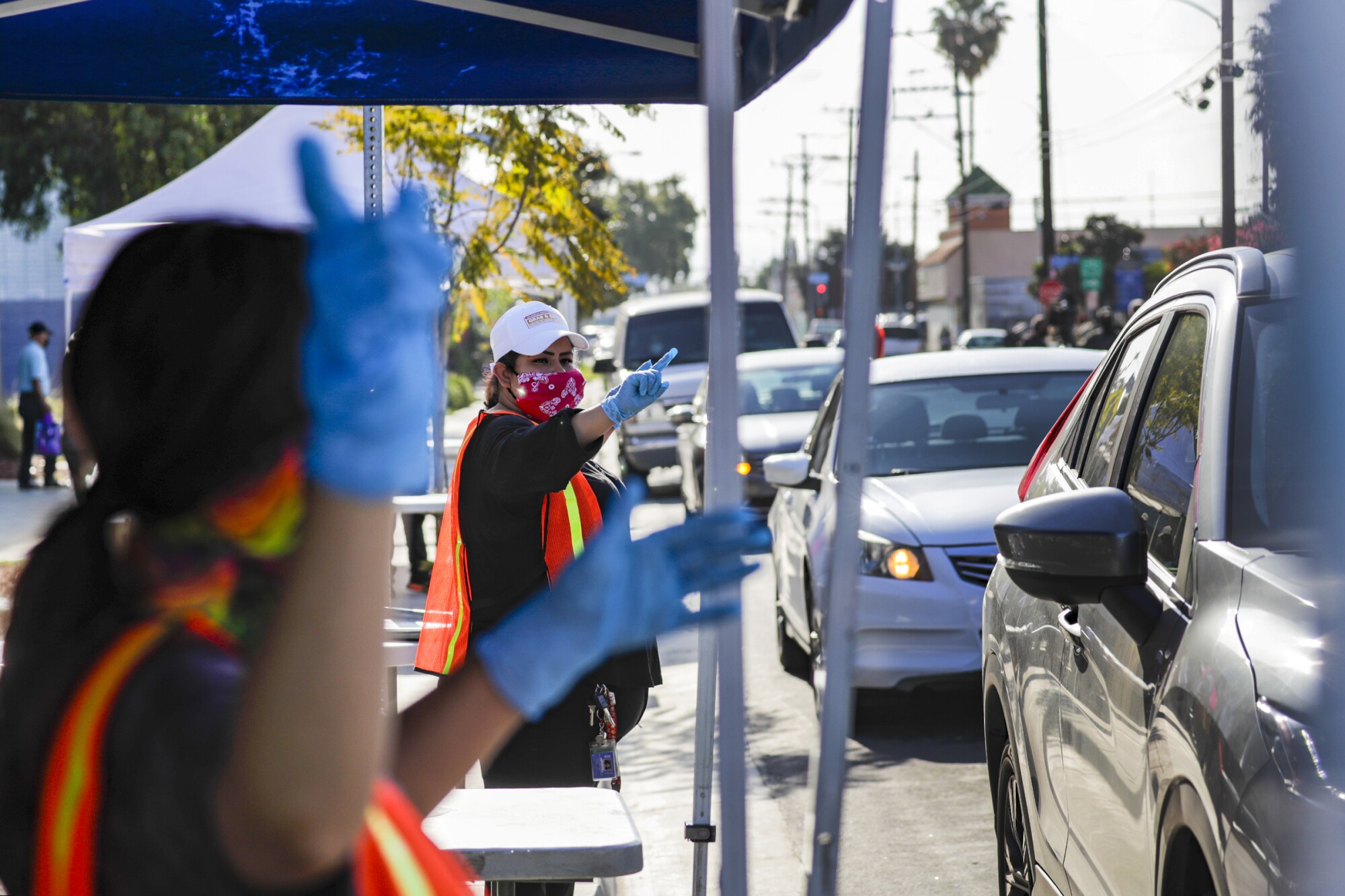 LAUSD cafeteria crew directs cars approaching meal bag distribution stations