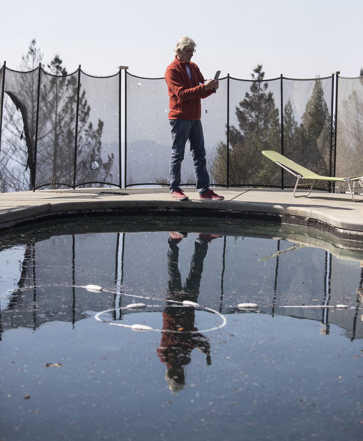 John Pascoe takes photographs after he and wife Jan survived the firestorm Monday morning.