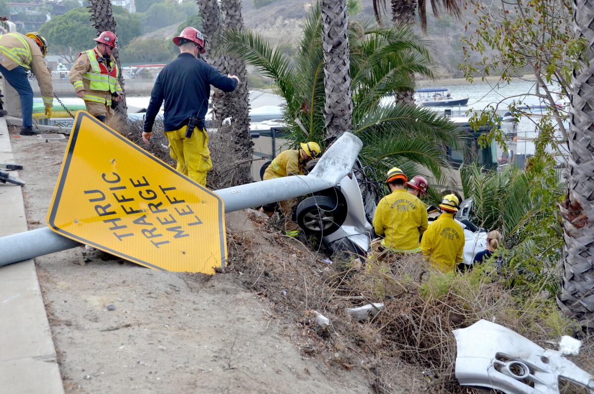 NBFD personnel extract the driver of a car that went over the side of Pacific Coast Highway.