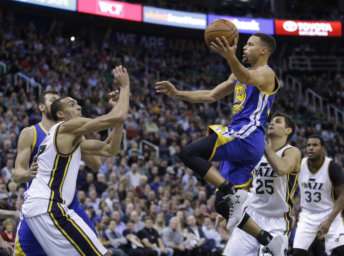 Warriors guard Stephen Curry (30) goes to the basket as Jazz' defenders Raul Neto (25) and Rudy Gobert, left, look on during the second quarter.