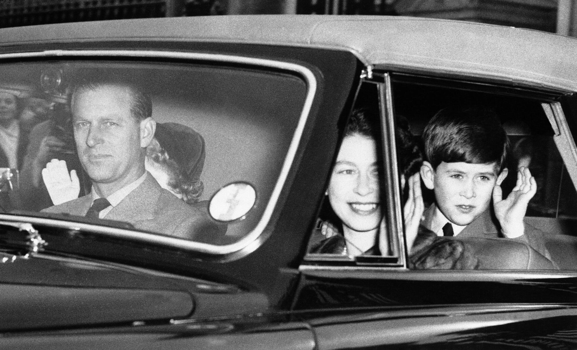 Prince Philip behind the wheel of a car with Queen Elizabeth II and a young Prince Charles and Princess Anne