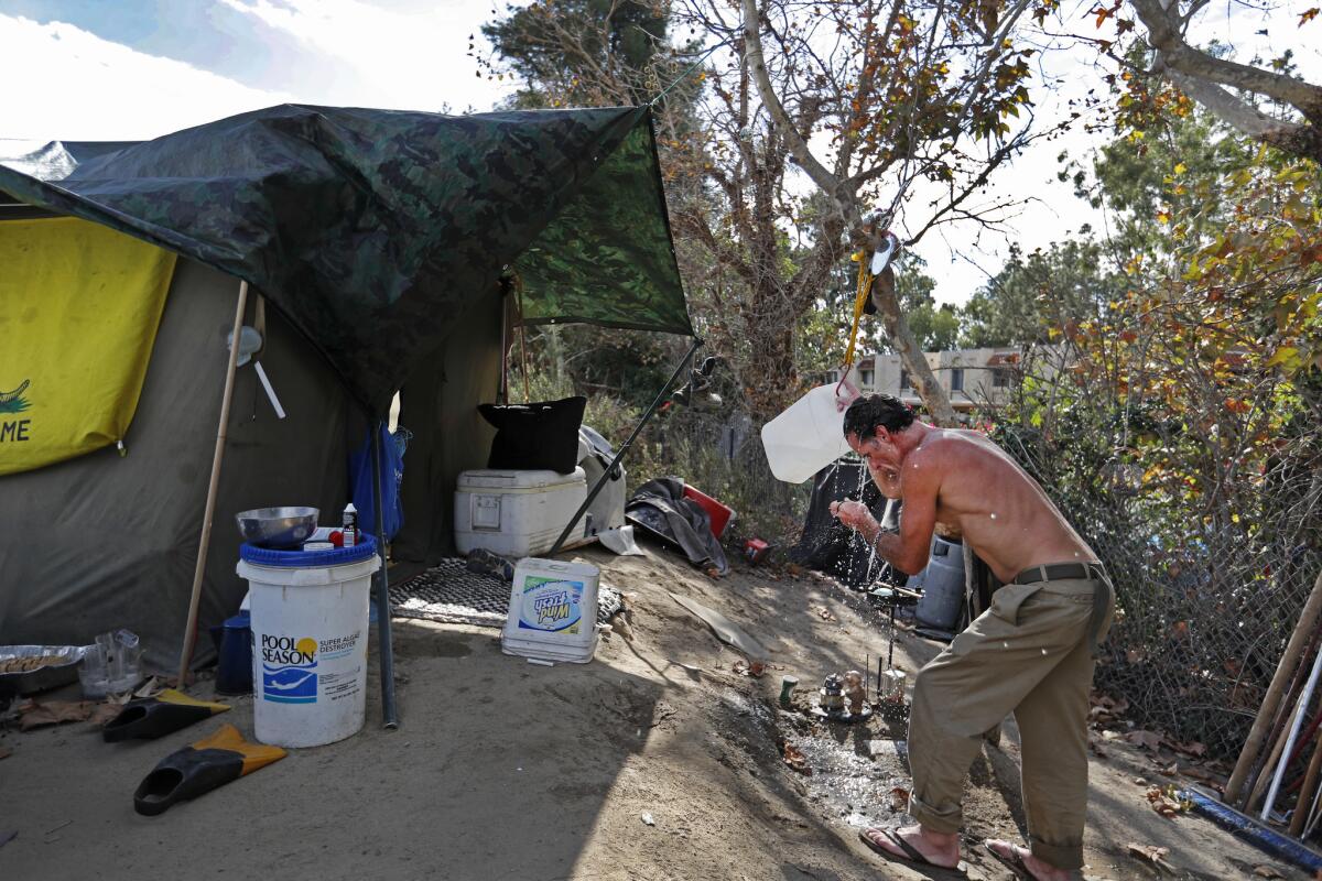 Homeless veteran Larry Ford showers in his camp. Homeless people are packing their belongings in preparation for Friday’s eviction.