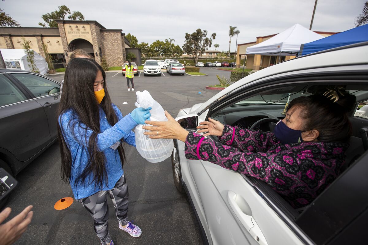Volunteer Julianne Akers hands a package of food to Elizabeth Xuan Nguyen