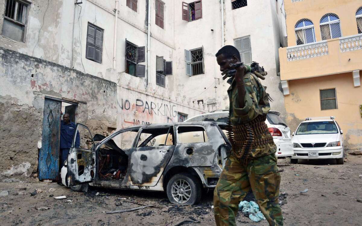 A Somali soldier walks past the shell of a car after an explosion on Sunday in central Mogadishu, the capital.