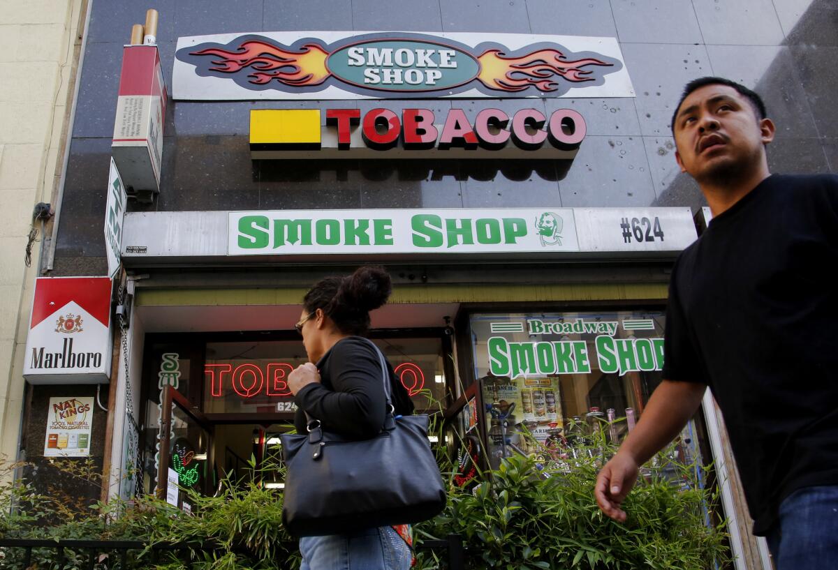 Pedestrians pass by a smoke shop on Broadway in downtown Los Angeles. Bay Area billionaire Tom Steyer has joined a a campaign proposing a ballot initiataive for a new $2-per-pack tax on cigarettes.