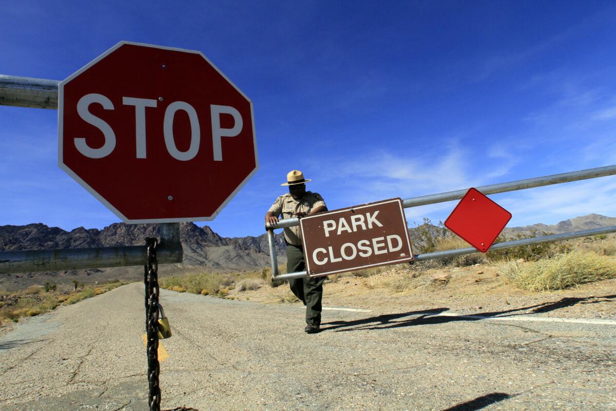 A park official closes the gate to Providence Mountains State Recreation Area in the Mojave Desert.