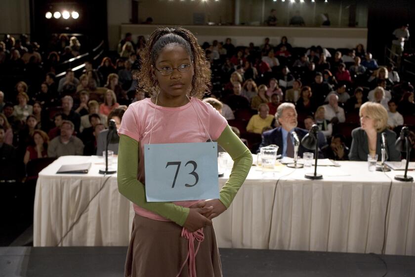 A young girl standing in front of a panel of judges and a large crowd