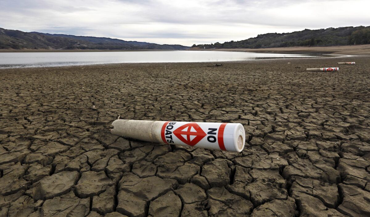 In this February 2014 photo, a warning buoy sits on the dry, cracked bed of Lake Mendocino near Ukiah, Calif.