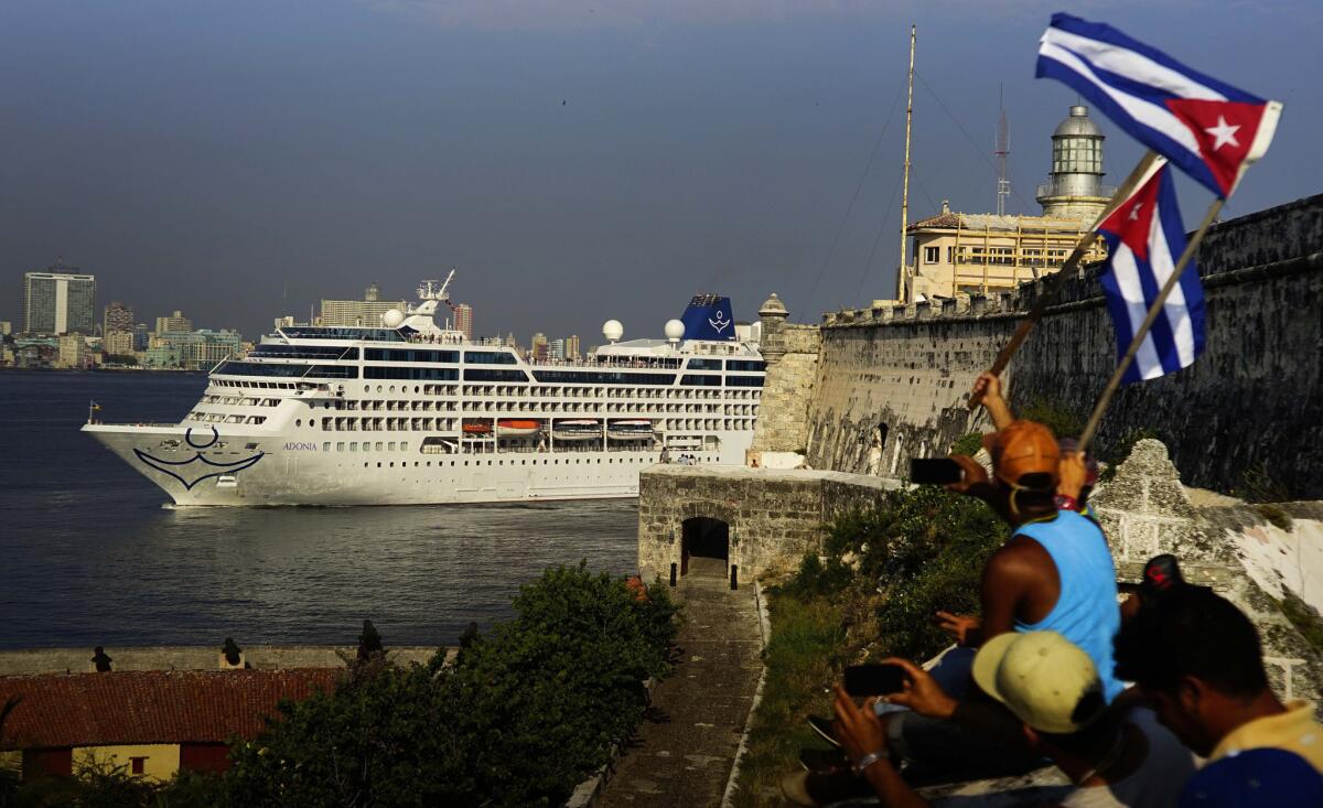 People waving Cuban flags greet passengers on Carnival's Adonia cruise ship as they arrive in Havana on Monday.