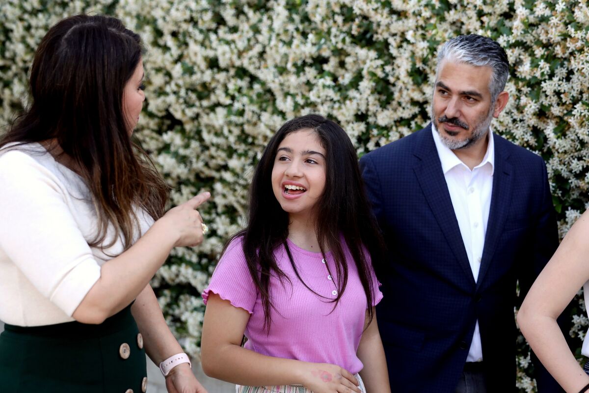 A girl with her parents in front of flowers