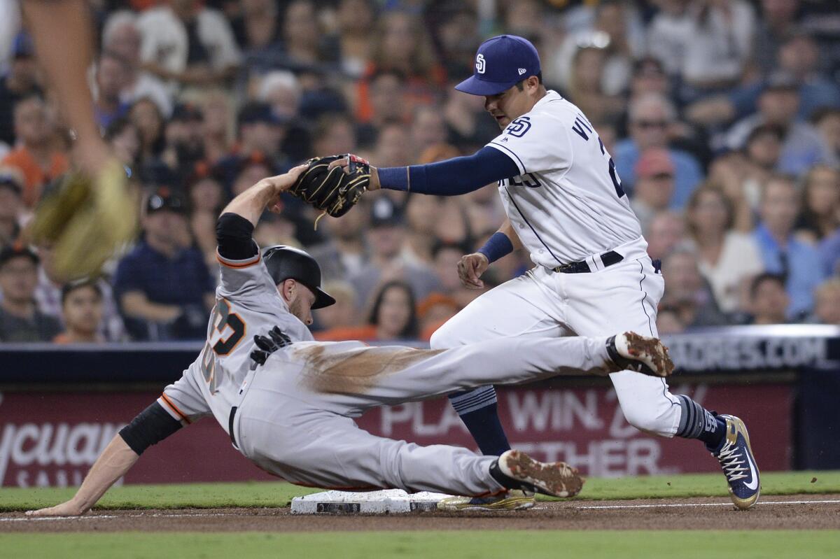 El tercera base mexicano de los Padres de San Diego, Christian Villanueva (derecha), elimina a Austin Slater, de los Gigantes de San Francisco en tercera base en el sexto inning del juego de la MLB que enfrentó a ambos equipos, el 30 de julio de 2018, en San Diego. (AP Foto/Orlando Ramirez)