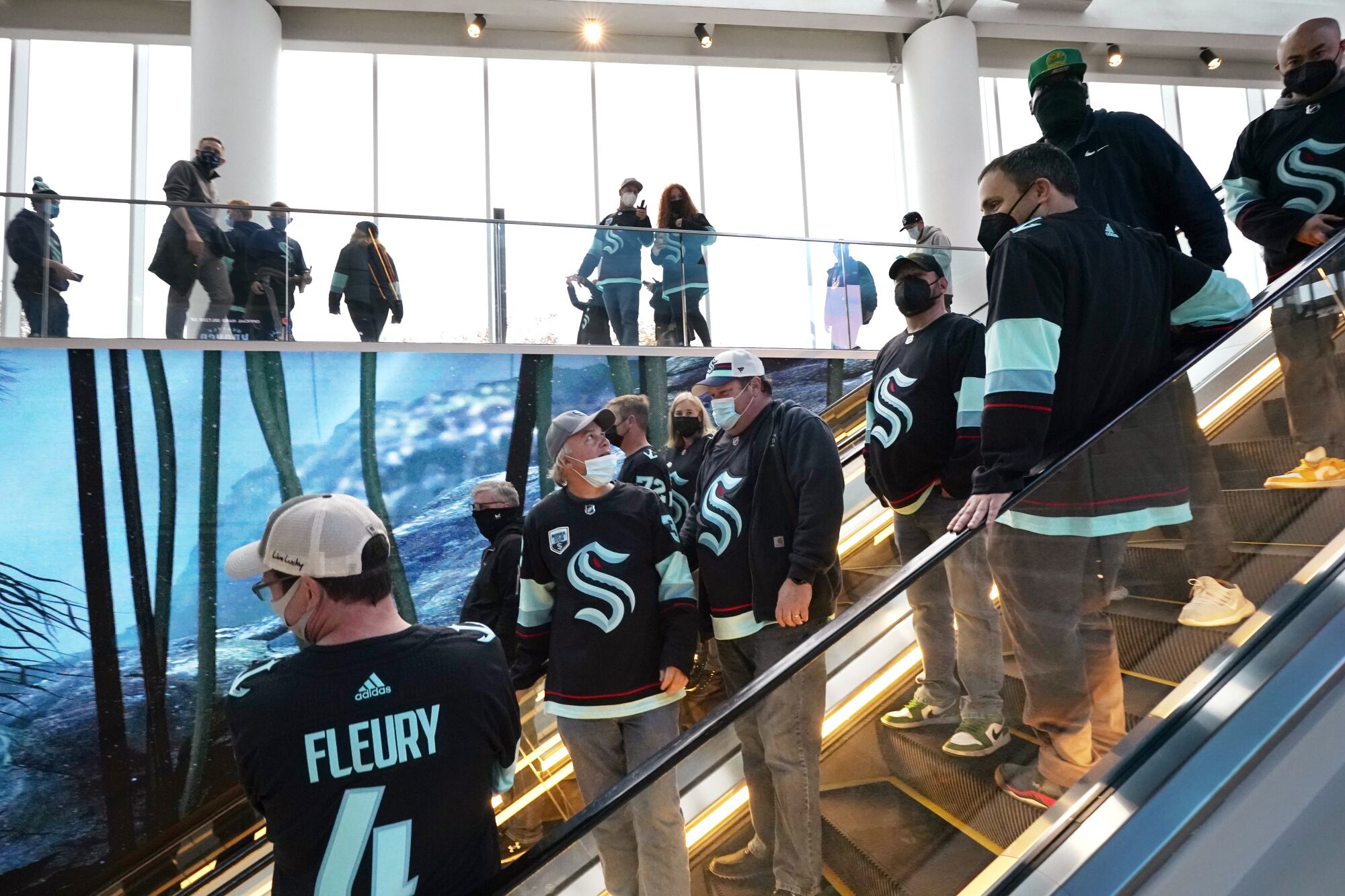 Fans take an escalator into the arena after entering Climate Pledge Arena for a hockey game.