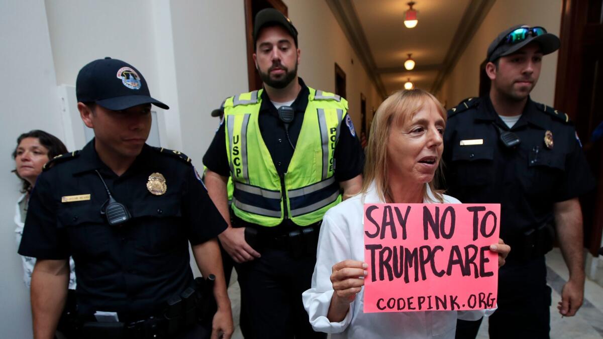 Medea Benjamin, cofounder of the protest organization Codepink, is escorted from the office of Senate Majority Leader Mitch McConnell on Monday, just before the GOP's healthcare repeal effort collapsed.