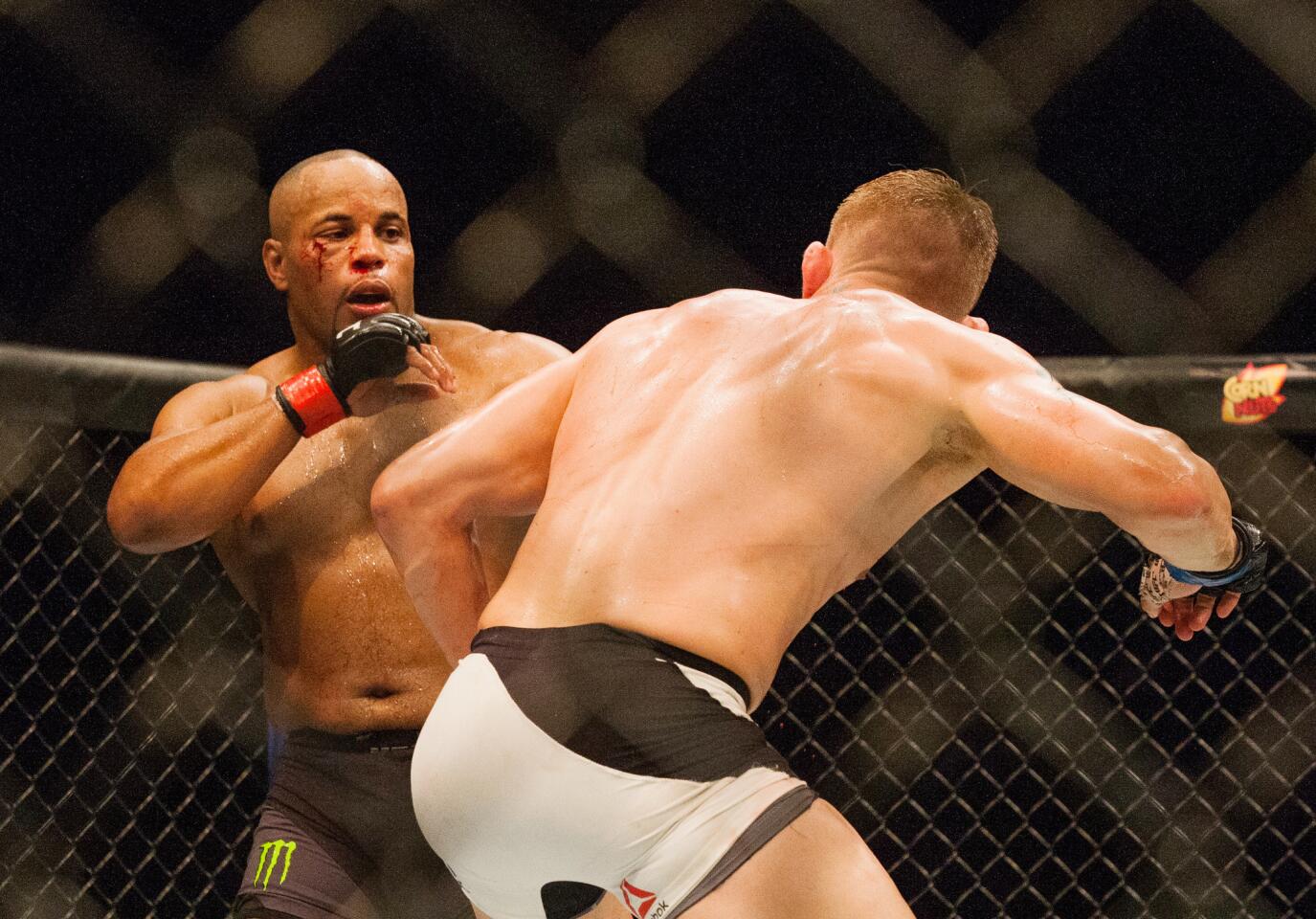 Daniel Cormier, left, and Alexander Gustafsson trade punches in the octagon during their light-heavyweight title fight on Saturday night at UFC 192 in Houston. Cormier retained his title by split decision.