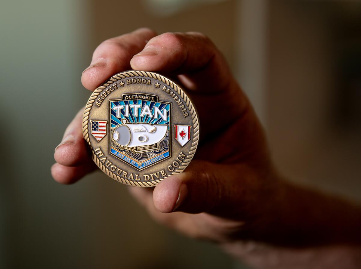 A Titan inaugural dive coin held by a hand
